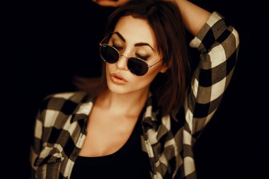 Gözlüklü ve ekose gömlekli bir kız.