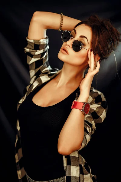Девушка в очках и клетчатой рубашке на темном фоне — стоковое фото