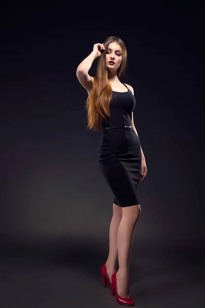 Vacker kvinna i sexig aftonklänning mot mörk bakgrund — Stockfoto