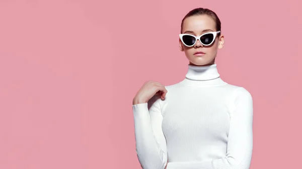 Fashion studio bild av vackra eleganta kvinnan i vit stickad golf och solglasögon poserar över rosa vägg — Stockfoto