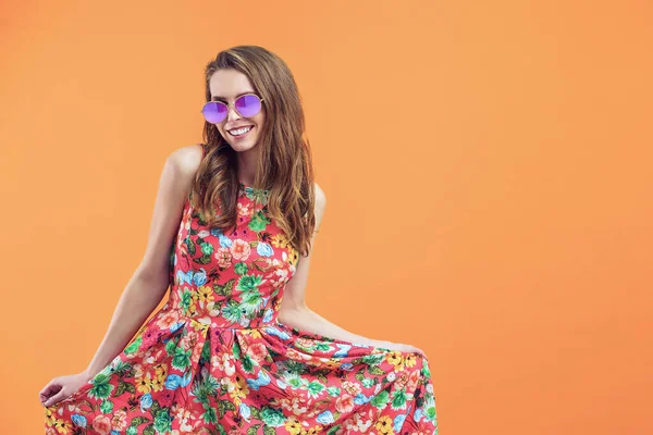 Chica en vestido floral emocionalmente posa sobre el fondo naranja —  Fotos de Stock