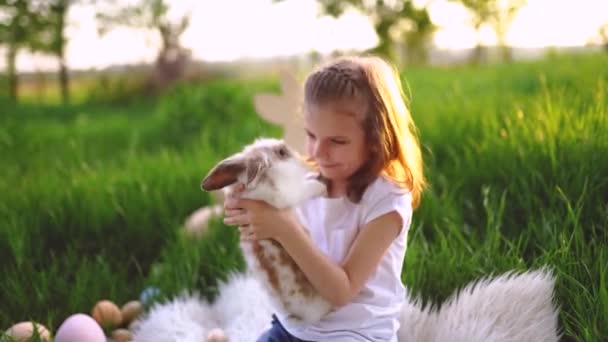 Une fille joue avec un lapin dans la rue. Faire des oreilles de lapin avec les mains. Pâques — Video