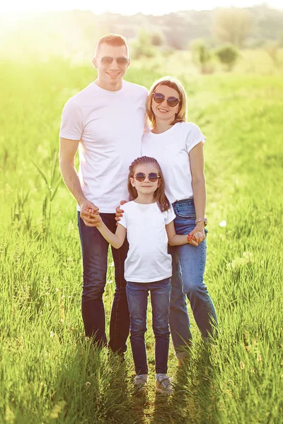 Photo A happy family in white T-shirts, sunglasses and jeans in the park. Summer — 스톡 사진