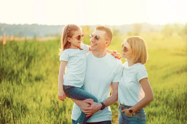 Φωτογραφία Μια ευτυχισμένη οικογένεια σε λευκό T-shirts, γυαλιά ηλίου και τζιν στο πάρκο. Καλοκαίρι — Φωτογραφία Αρχείου