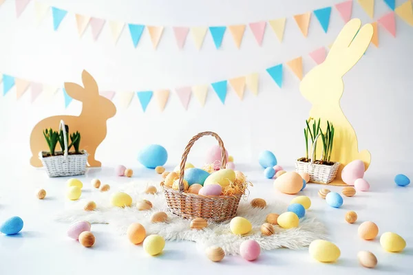 Easter. Many colorful Easter eggs with bunnies and baskets. Easter decoration of the room, childrens room for games. Basket with carrots and rabbits. Easter photo shoot. Nest, eggs, boxes of hay — Stock Photo, Image