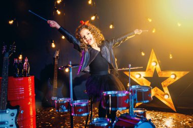 Güzel bir kız siyah arka planda davul çalıyor.