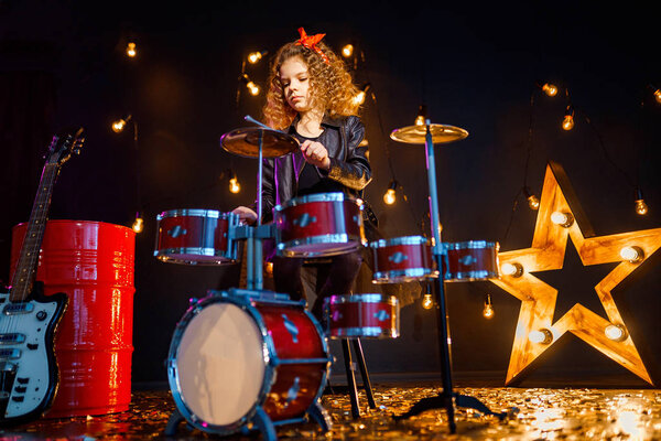Beautiful girl playing the drums on a black background