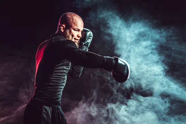 Боксер-спортсмен дерётся на черном фоне с дымом. Концепция бокса — стоковое фото