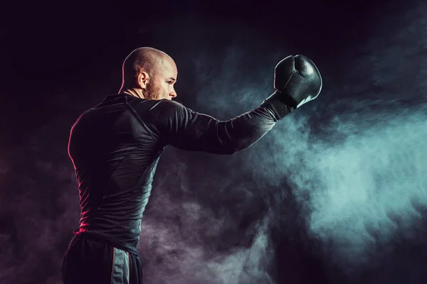 Lutando boxeador desportista, batendo uppercut no fundo preto com fumaça. Conceito de desporto de boxe — Fotografia de Stock