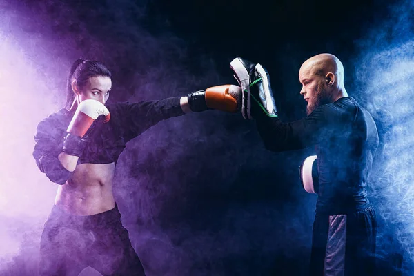 Mujer haciendo ejercicio con entrenador en la lección de boxeo y defensa personal — Foto de Stock