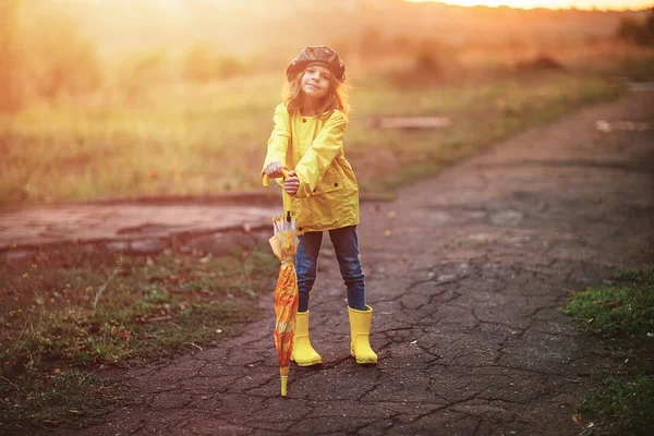 Happy funny child girl with umbrella in rubber boots