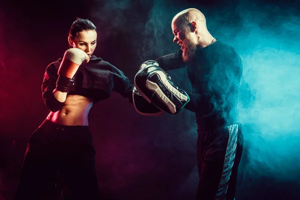 Mujer haciendo ejercicio con entrenador en la lección de boxeo y defensa personal — Foto de Stock