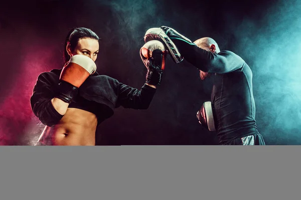 Mujer haciendo ejercicio con entrenador en la lección de boxeo y defensa personal — Foto de Stock