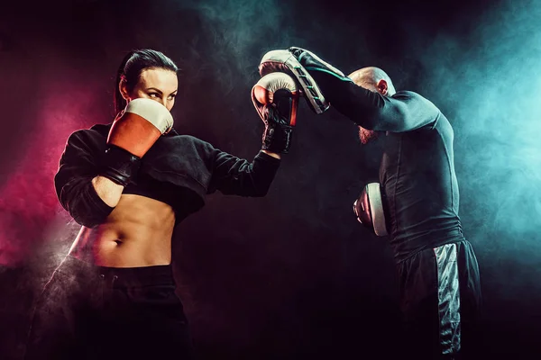 Mujer haciendo ejercicio con entrenador en la lección de boxeo y defensa personal — Foto de Stock