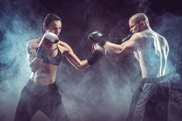 Mujer sin camisa haciendo ejercicio con entrenador en el boxeo y autodefensa lección, estudio, humo de fondo. Lucha femenina y masculina — Foto de Stock