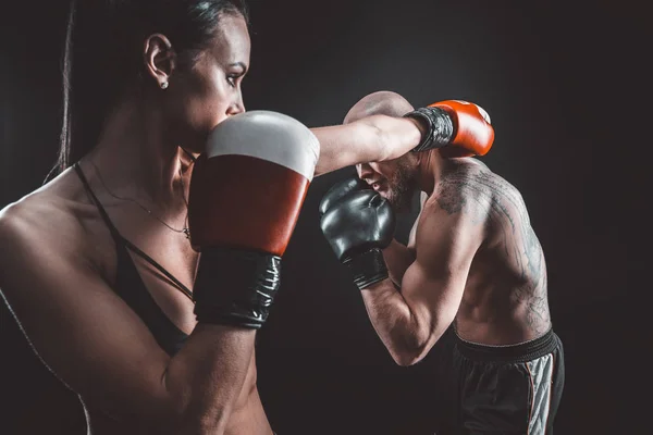 Mujer sin camisa haciendo ejercicio con entrenador en el boxeo y autodefensa lección, estudio, humo de fondo. Lucha femenina y masculina — Foto de Stock