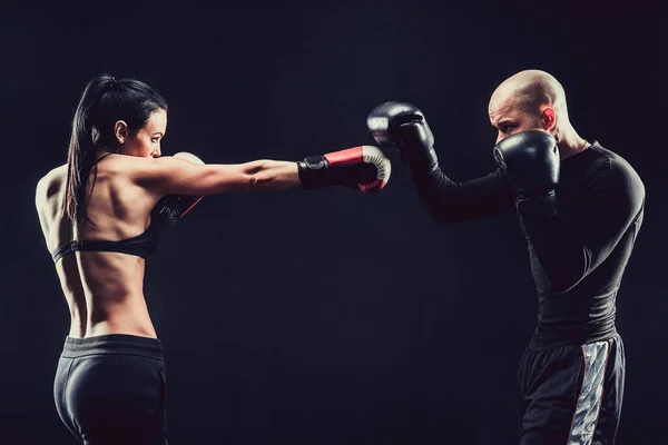 Mujer sin camisa haciendo ejercicio con entrenador en el boxeo y autodefensa lección, estudio, humo de fondo. Lucha femenina y masculina — Foto de Stock