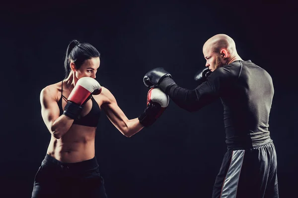 Mujer sin camisa haciendo ejercicio con entrenador en el boxeo y autodefensa lección, estudio, humo de fondo. Lucha femenina y masculina —  Fotos de Stock