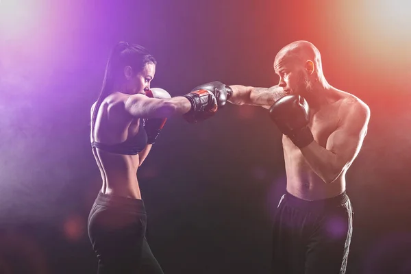 Mujer sin camisa haciendo ejercicio con entrenador en el boxeo y autodefensa lección, estudio, humo de fondo. Lucha femenina y masculina —  Fotos de Stock