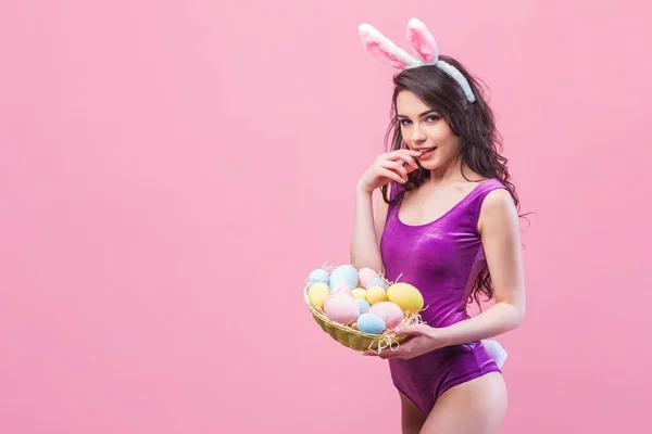 Attractive hot young woman wearing bodysuit and bunny ears posing on pink background — Stock Photo, Image