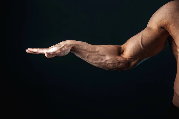 Gespannen arm, aders, bodybuilder spieren op een donkere achtergrond, isoleren — Stockfoto