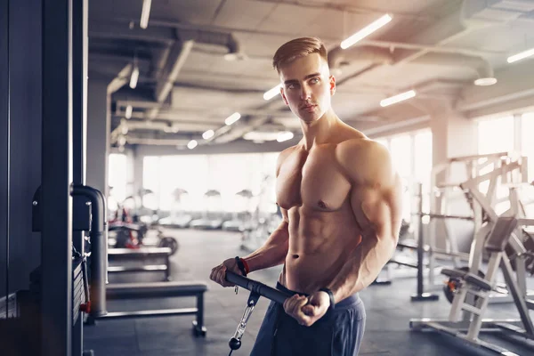 Muskulös Fitness kroppsbyggare gör tung viktövning för biceps på maskin med kabel i gymmet — Stockfoto