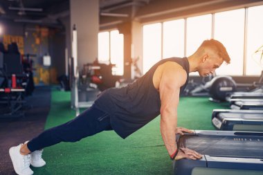 Spor salonunda şınav çeken genç bir sporcu. Kaslı ve güçlü adam egzersiz yapıyor..