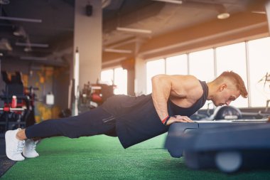 Spor salonunda şınav çeken genç bir sporcu. Kaslı ve güçlü adam egzersiz yapıyor..