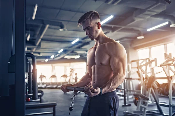 Muscular Fitness culturista haciendo ejercicio de peso pesado para bíceps en la máquina con cable en el gimnasio —  Fotos de Stock