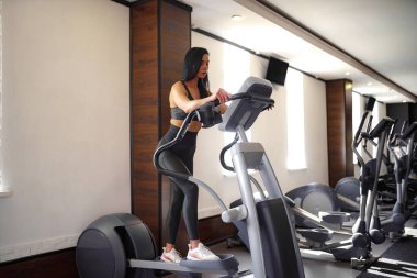Spor salonunda antrenman yapmak, spor salonunda çalışmak, spor kıyafetinin içinde poz vermek.