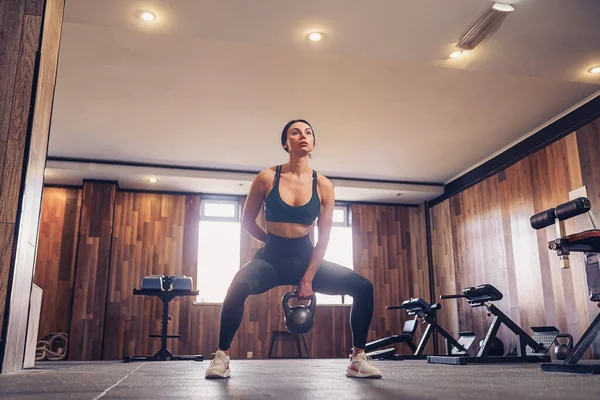 Mulher fitness adulto jovem fazendo exercício de balanço com um kettlebell como parte de um treino de fitness — Fotografia de Stock