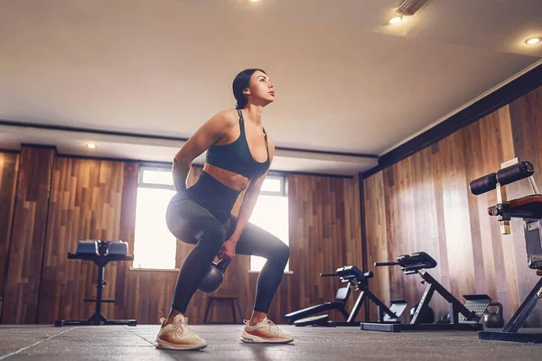 Junge erwachsene Fitnessfrau beim Schaukeltraining mit der Kettlebell als Teil eines Fitnesstrainings — Stockfoto