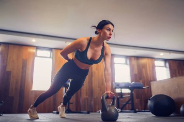 Genç motive olmuş bir kız spor salonunda kettlebell kullanıyor, uzun bir fotoğraf, fotokopi alanı.