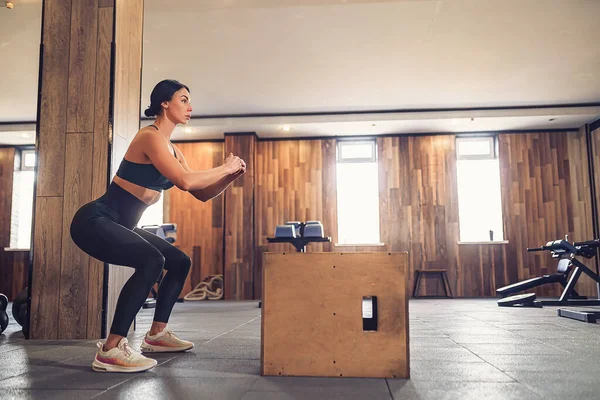 Genç bir kadının spor salonunda bir kutuyla antrenman yaptığı fotoğraf. Crossfit spor salonunda atlayan bayan sporcu. — Stok fotoğraf