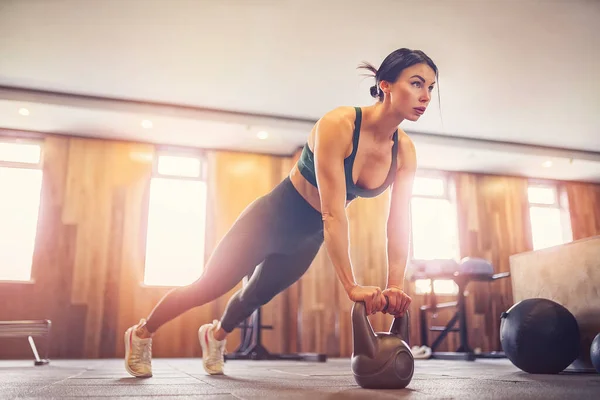 Joven chica motivada haciendo ejercicio de tablón usando pesas en el gimnasio, foto de cuerpo entero, espacio para copiar — Foto de Stock