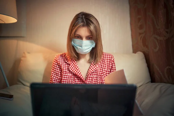 Jeune femme d'affaires dans un masque de protection médicale travaille de la maison à l'ordinateur pendant l'isolement et la quarantaine. Épidémie de coronavirus virale, épidémie de grippe et roman covid ncov. Reste à la maison — Photo