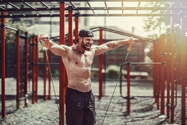 Fitness man exercising with stretching band in outdoor gym. — Stock Photo, Image