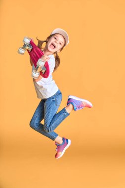 Aktif ve mutlu. Çocuk para tahtasıyla eğleniyor. Gülen yüzlü çocuk kaykay yapıyor. Kızlar için kaykay kaykayı. Hadi gidelim. Beyaz arka planda kız biniciliği. Yaz tatili