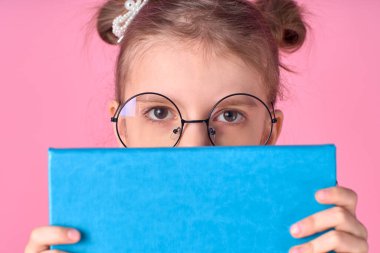 Onun güzel seksi, çekici, neşeli, pozitif okul kızının portresi. El ele tutuşup açık sınav hazırlıklarının arkasına saklanıyor. Pembe arka planda izole edilmiş.