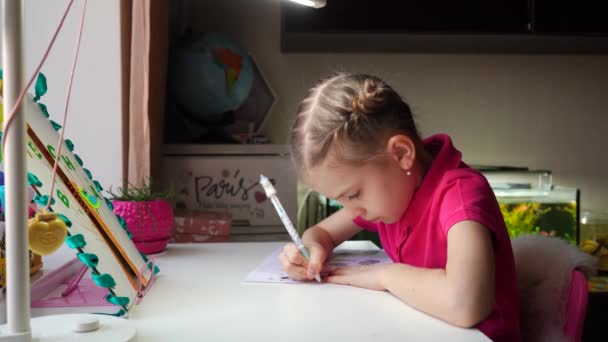Holčička píše a kreslí. Dělám domácí úkoly. Roztomilé děvče. — Stock video