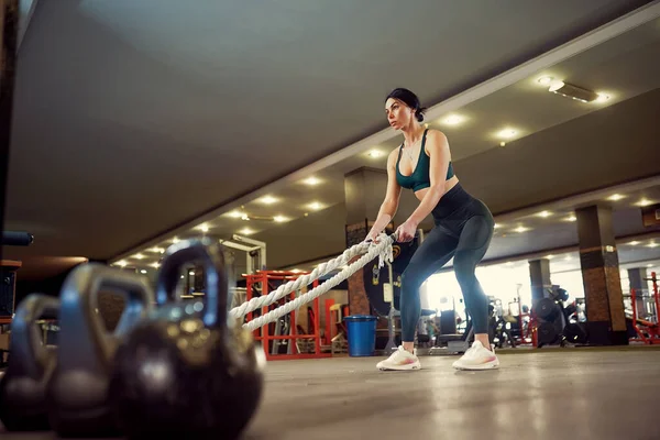 Kaukasisch fitte Frau in Sportkleidung bereitet sich im Fitnessstudio auf das Training mit Kampfseilen vor — Stockfoto