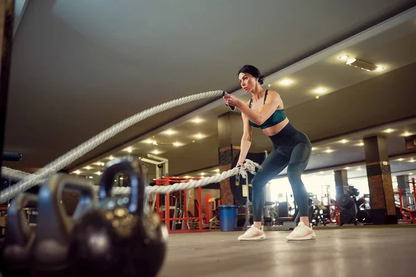 Caucasiano mulher em forma vestida em sportsoutfit fazendo treino com cordas de batalha no ginásio — Fotografia de Stock