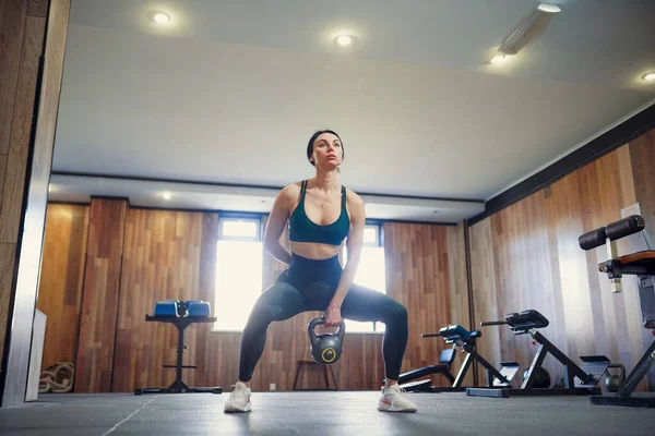 Junge erwachsene Fitnessfrau beim Schaukeltraining mit der Kettlebell als Teil eines Fitnesstrainings — Stockfoto