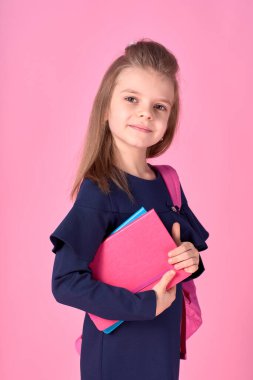 Okul konseptine geri dönelim. Kendine güveni tam, güzel ve zeki bir kızın okul üniforması içinde pembe parlak bir sırt çantası olan yarı dönüştürülmüş fotoğrafı.