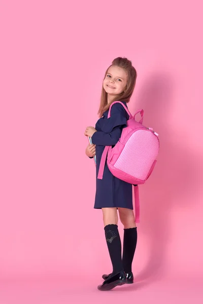 Voltar ao conceito da escola Meia foto virou retrato de linda menina inteligente confiante bonita com caderno copybook vestindo vestido uniforme escolar rosa mochila brilhante isolado — Fotografia de Stock