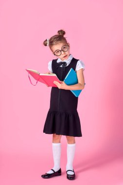 Gözlükleri ve pembe arka plan kitapları olan sevimli küçük bir kız. Mesaj atmak için yer var. Okuma konsepti