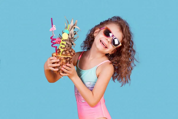 Красива дівчина в барвистому купальнику і сонцезахисних окулярах тримає ананасовий коктейль — стокове фото
