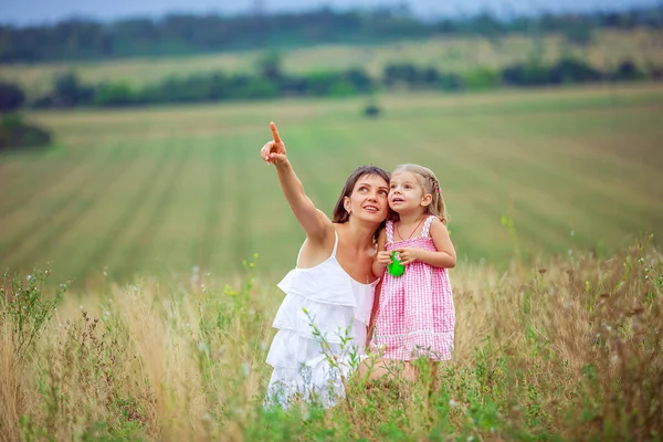 Счастливые мать и дочь проводят время вместе на открытом воздухе, указывая пальцами и с энтузиазмом глядя вверх, с удовольствием проводить время в сельской местности — стоковое фото