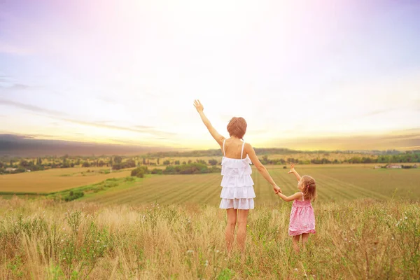 Задний вид на красивую пару мать и милая дочь стоя, когда подняли руки наслаждаясь видом на поле заката, пространство Sopy — стоковое фото