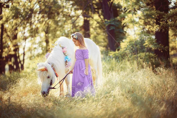 Meisje in paarse jurk knuffelende witte eenhoorn paard. Dromen komen uit. Sprookje — Stockfoto